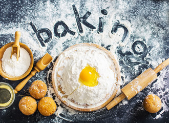 Baking ingredients. Bowl, eggs, flour, eggbeater, rolling pin and eggshells on black chalkboard...