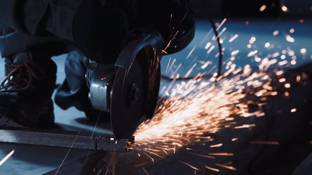 Man cutting metal using grinding machine in hangar