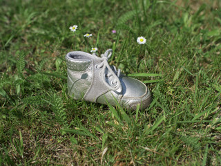 Silver baby shoe on grass - from the side