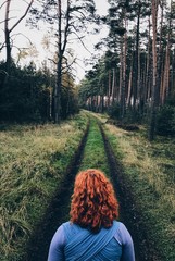 Red head woman on the forest path.