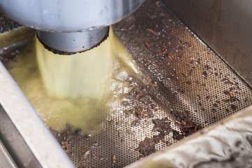 Olive pomace oil flowing from a pipe after the separation process from the pure oil