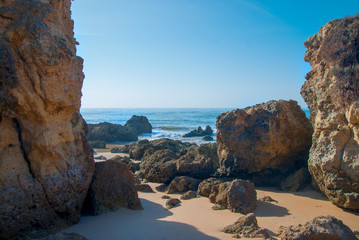 Fototapeta premium Wild summer ocean beach, Portugal. Clear sky, Rocks on sand