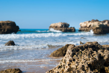 Wild summer ocean beach, Portugal. Clear sky, Rocks on sand