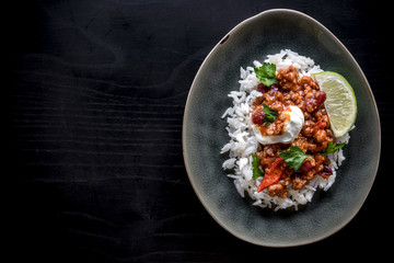 Minced lamb meat in chilli sauce and rice served on dark background with blank space