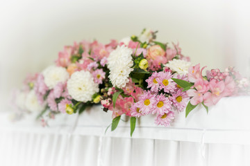 Beautiful wedding floral decoration on a table in a restaurant.White tablecloths, bright room.