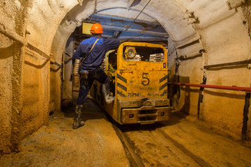 Miner with electrical locomotive underground ore mine shaft tunnel