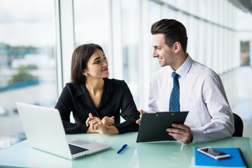 Client signing a document in an office with a businesswoman looking the contract. Office work