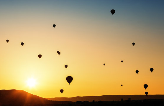 Balloons flying in the sky at sunrise.