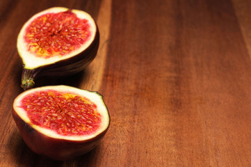 a fig cut into two pieces on a wooden dark brown plate, place for text