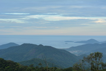 Vista de Ubatuba de cima da Serra do Mar, com camadas de montanhas azuis que acabam no mar. 