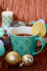 Turquoise mug with pattern filled with tea and slice of lemon with background 