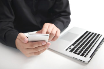 Man in a black shirt using mobile phone and laptop