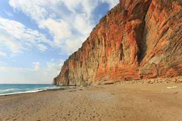 Fototapeta na wymiar Paradise beach with large red rock descending to the sea