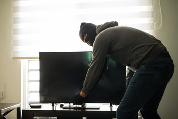 Man stealing tv in a house
