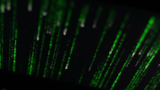 Footage of computer display screen with green moving text with code in the terminal software