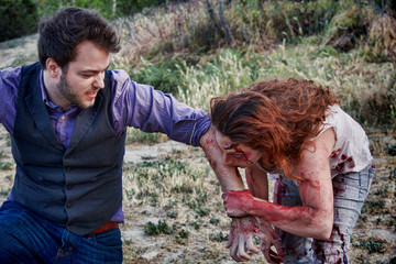 A grotesque and bloody female zombie bites a man's arm