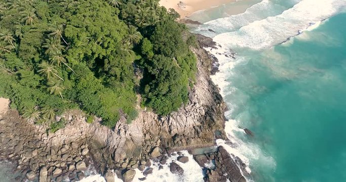 Aerial drone view of beautiful tropical island  sandy beach and sea waves crashing coastline crocks during sunny summer day