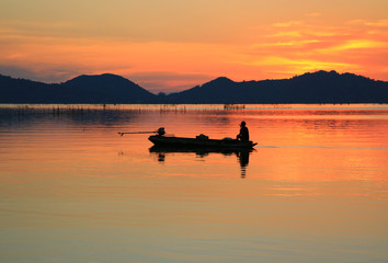 silhouette fisherman in the boat on sunrise.