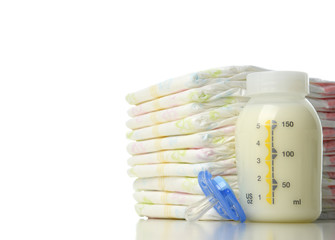 New born child stack of diapers nipple soother and baby feeding bottle with milk 