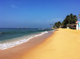 Fototapeta na wymiar Walking along the sun drenched beach in a tropical paradise
