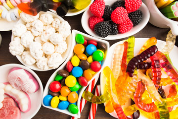 Colorful candies over brown wooden background