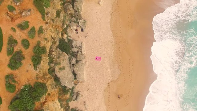 Aerial view of beautiful woman alone in an amazing and unspoiled beach in the spain coast