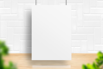 Blank white poster hanging at marble wall and wood floor room with blur leaf foreground,Ecology or Organic concept,Mock up for display of design.