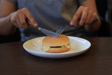 Woman prepare cutting burger in two halfs select focus, Holding cutting burger, Cutting burger in two halfs on table low light