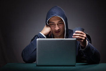 Young man wearing a hoodie sitting in front of a laptop computer