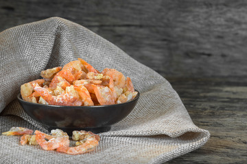dried shrimp-ingredient of many thai food in a ceramic dish on calico fabric with old and crack wooden surface background.
