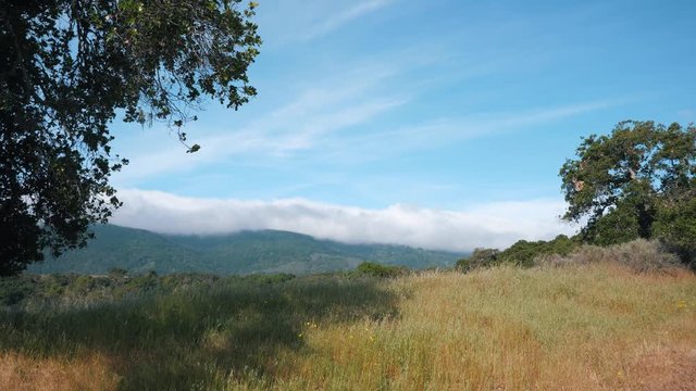 Picturesque view of meadow mountains and clouds laying over them