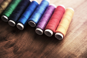 Colored sewing threads on a old work table with impressional feel.
