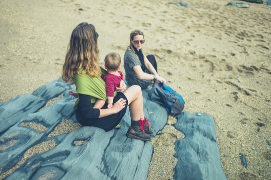 Two women with a baby sitting on the beach