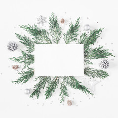 Christmas composition. Paper blank, pine tree branches, christmas silver decorations on white...