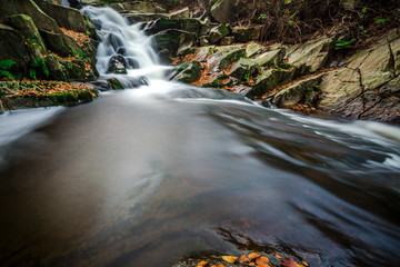 Fototapeta na wymiar Mountain stream with waterfall in an autumn forest. time exposure