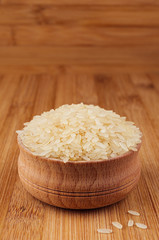 White rice basmati in wooden bowl on brown bamboo board, closeup. Healthy dietary cereals  background.