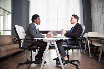 Fototapeta na wymiar Two young businessmen, white desk, job interview, teamwork
