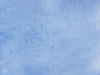 Pale light blue sky with small white clouds background, with consistently spreading transparent 