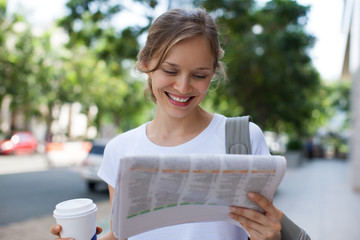 Smiling Woman Reading Newspaper on Street