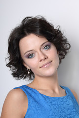 Beautiful young brunette woman with clean skin and make-up on grey background