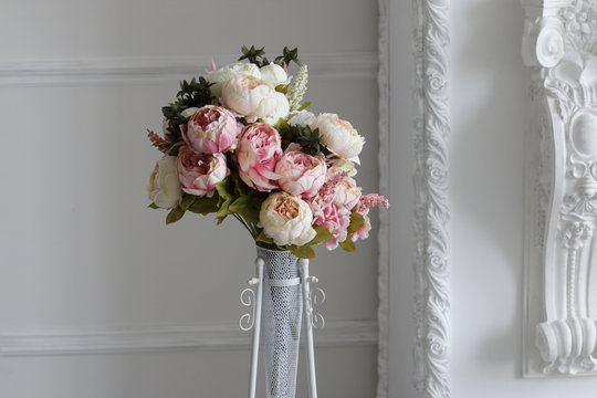 bouquet of peonies in vase against white wall in photo studio