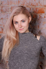 Fototapeta premium portrait of beautiful blonde woman in striped blouse posing near brick wall