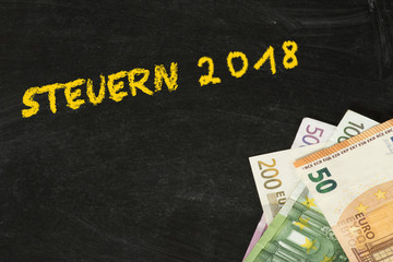 Kreidetafel, Euro Geldscheine und Steuern für das Jahr 2018