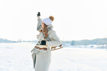 Winkende Frau mit Schlittschuhen im Winter