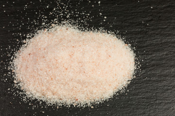 heap of rose-colored himalaya salt on slate plate