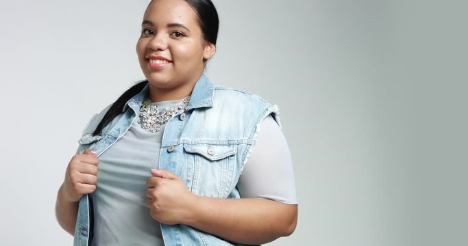 Smiling cute big African American girl in blue shirt, black pants and a denim vest isolated on white. casual style plus size model