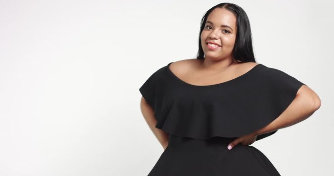 Confident strong young plus size African American model wearing a black short twirly dress flirting with camera isolated on white Slowmotion from 60fps