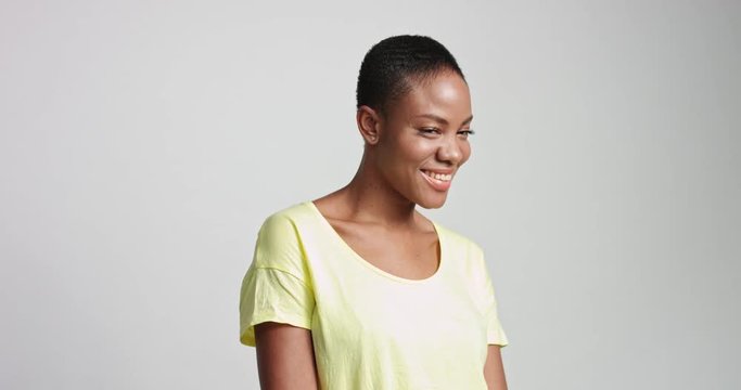 Attractive fit African American female model wearing a casual light blue short sleeve shirt on white background and smiling