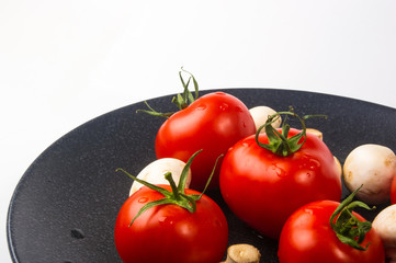 fresh tomatoes and mushrooms - champignons on black plate