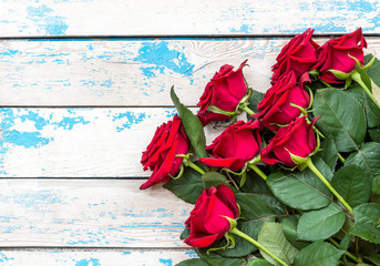 Red roses on a old blue wooden background. Top view.